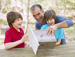 Smiling father with his two sons, holding a birdfeeder